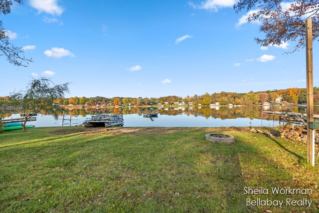 view of yard featuring a water view, a dock, and a fire pit