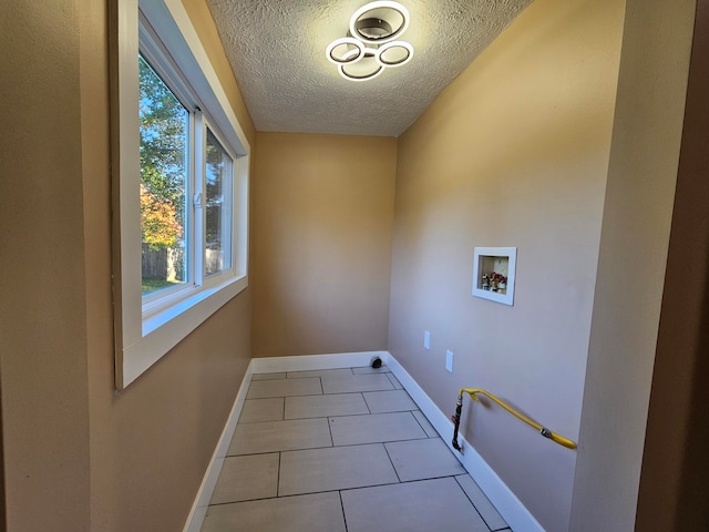 laundry area featuring a textured ceiling, washer hookup, and light tile patterned floors