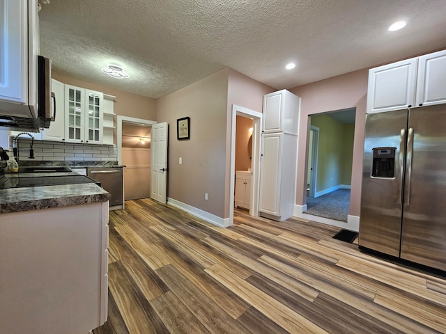 kitchen featuring hardwood / wood-style floors, appliances with stainless steel finishes, a textured ceiling, and white cabinetry