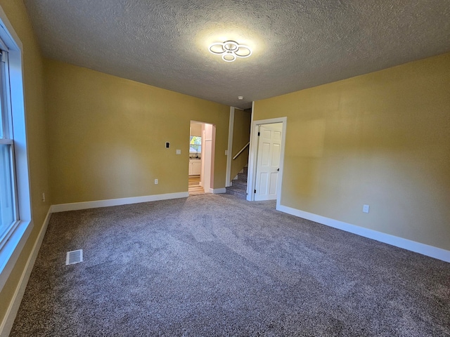 carpeted spare room featuring a textured ceiling