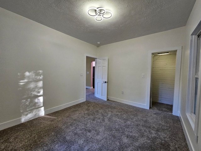 unfurnished bedroom with dark carpet, a textured ceiling, and a closet