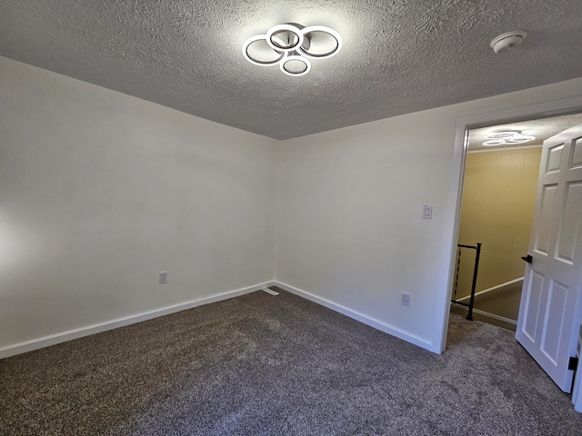 spare room featuring dark colored carpet and a textured ceiling