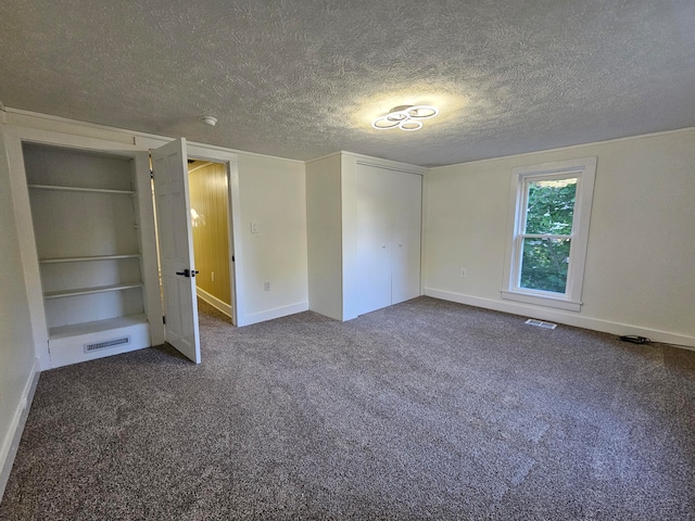 unfurnished bedroom featuring a textured ceiling and dark colored carpet