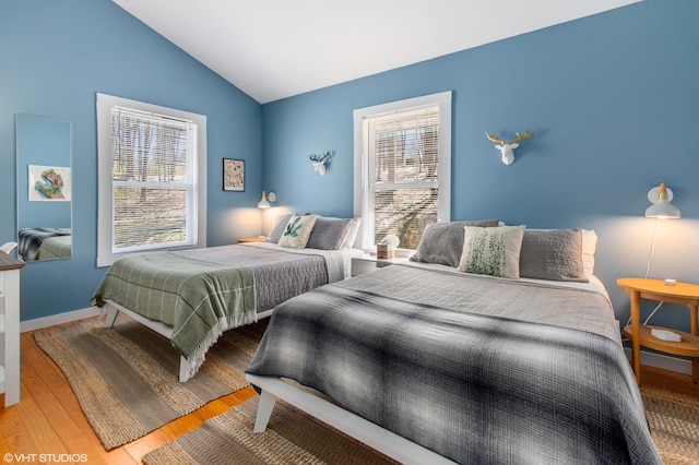 bedroom featuring hardwood / wood-style floors, vaulted ceiling, and multiple windows