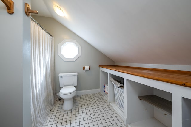 bathroom with toilet, lofted ceiling, and tile patterned flooring