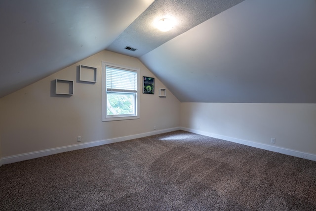 additional living space with a textured ceiling, carpet, and vaulted ceiling