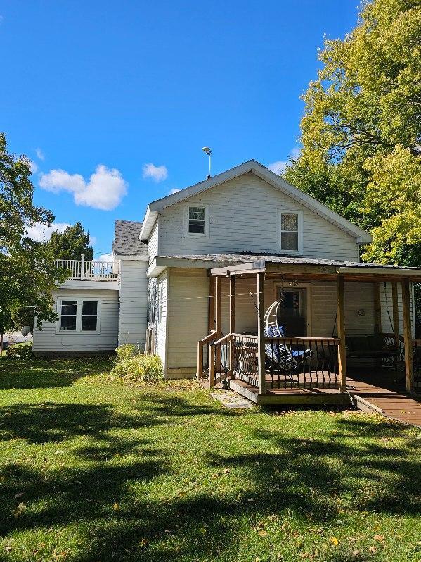 back of property with a deck and a lawn