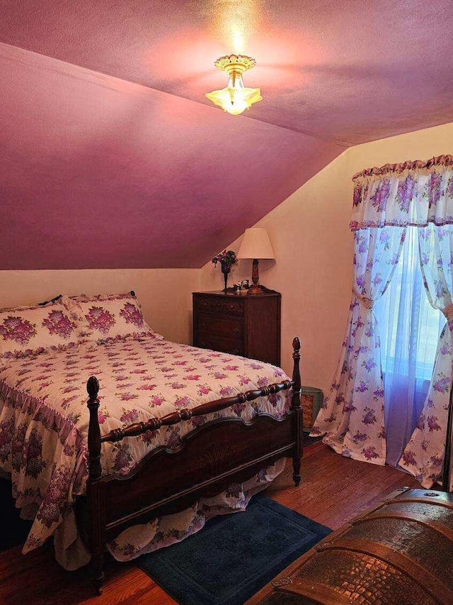 bedroom featuring a textured ceiling, hardwood / wood-style flooring, and vaulted ceiling