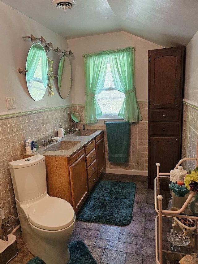 bathroom featuring toilet, vaulted ceiling, tile walls, vanity, and a textured ceiling