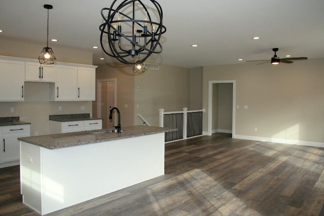 kitchen featuring sink, an island with sink, white cabinetry, dark stone counters, and dark hardwood / wood-style floors