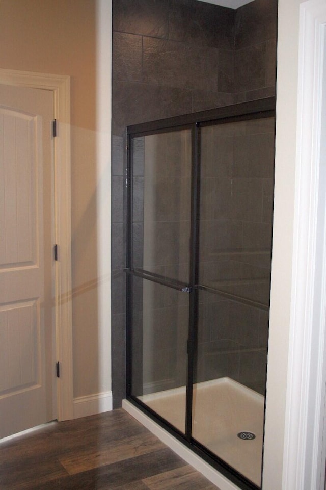 bathroom with hardwood / wood-style flooring and a shower with shower door