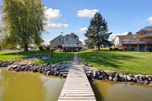 view of dock with a yard and a water view