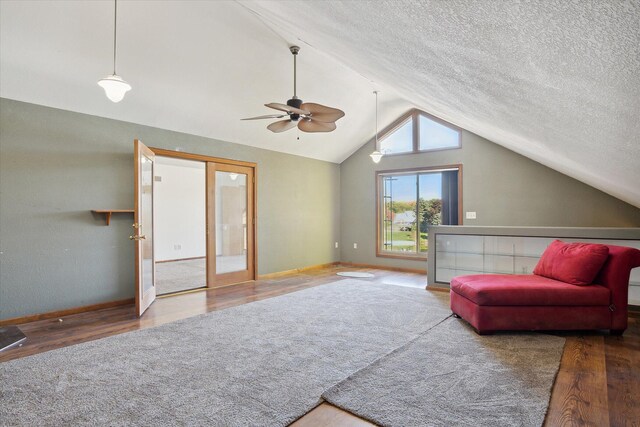 living room featuring a textured ceiling, ceiling fan, wood-type flooring, and vaulted ceiling