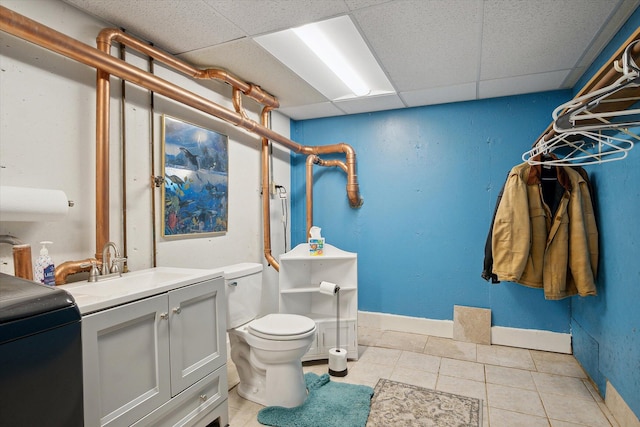 bathroom featuring vanity, toilet, a drop ceiling, and tile patterned flooring