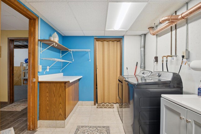 clothes washing area with light hardwood / wood-style flooring, washer and dryer, and cabinets