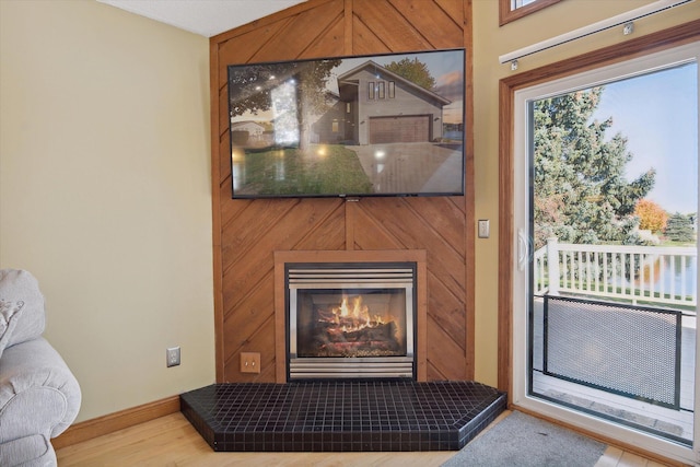 room details with wood walls, hardwood / wood-style flooring, and a tile fireplace