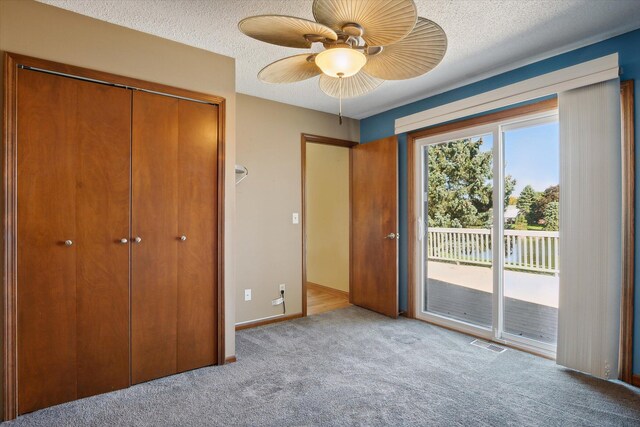 unfurnished bedroom with a textured ceiling, light carpet, access to exterior, and a closet