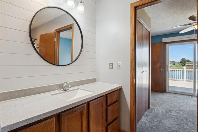 bathroom featuring vanity, a textured ceiling, wooden walls, and ceiling fan