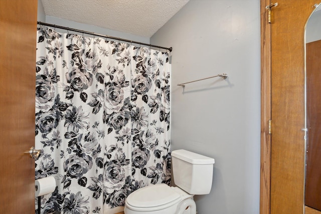 bathroom with toilet, a textured ceiling, and a shower with shower curtain