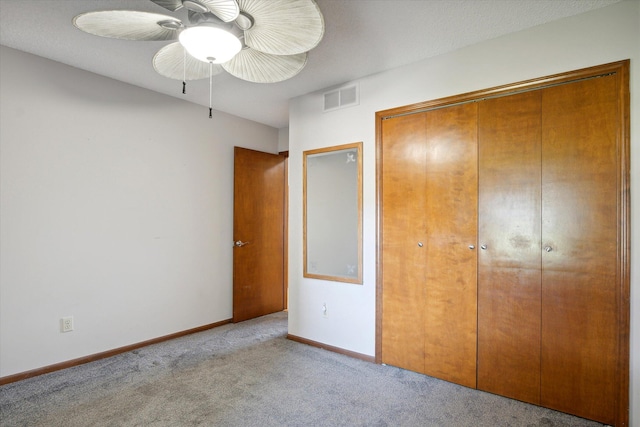 unfurnished bedroom featuring a closet, light colored carpet, and ceiling fan