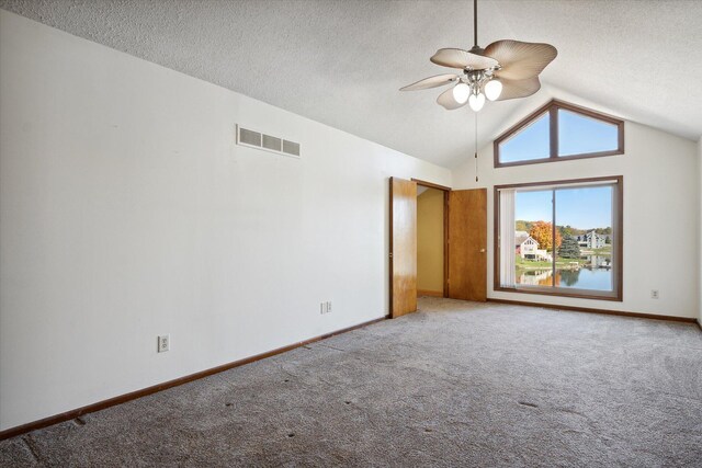 interior space featuring a textured ceiling, ceiling fan, light carpet, vaulted ceiling, and a water view