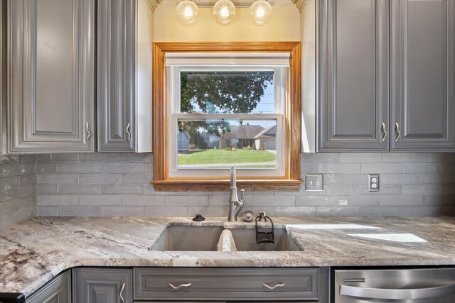 kitchen with gray cabinets, dishwasher, light stone countertops, and sink