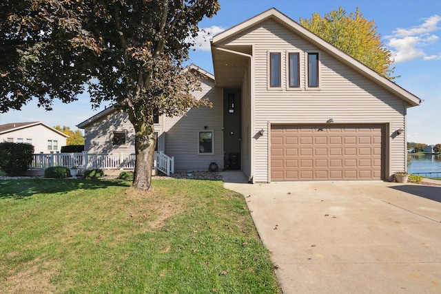 view of property featuring a front lawn, a garage, and a water view