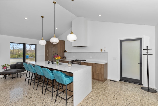 kitchen with a large island with sink, lofted ceiling, a kitchen breakfast bar, sink, and decorative light fixtures