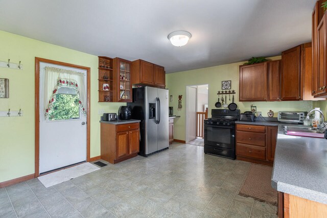 kitchen with sink, black gas stove, and stainless steel refrigerator with ice dispenser