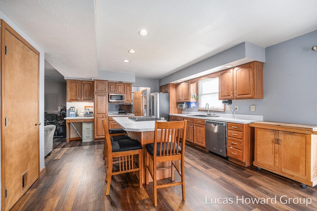 kitchen with a breakfast bar area, dark hardwood / wood-style flooring, stainless steel appliances, sink, and a center island