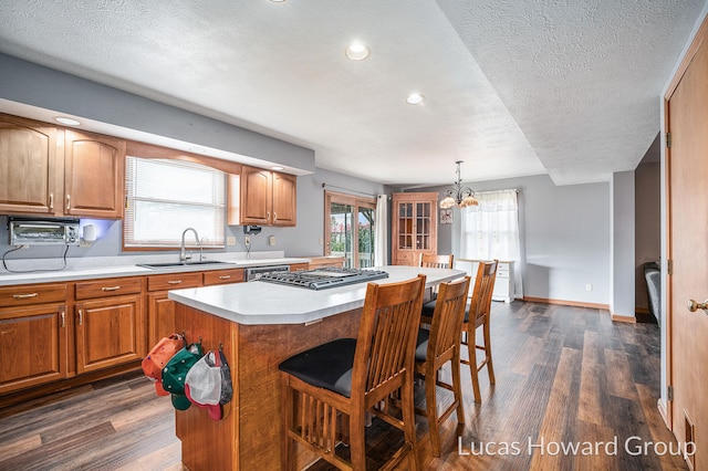 kitchen featuring dark wood-type flooring, a wealth of natural light, decorative light fixtures, and a kitchen island