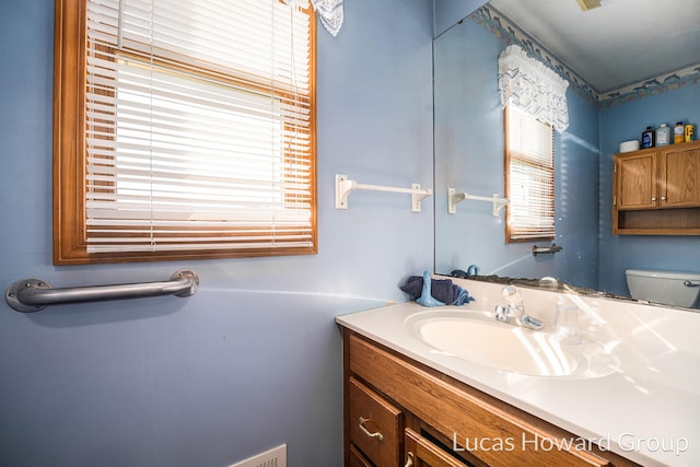 bathroom featuring a wealth of natural light, vanity, and toilet