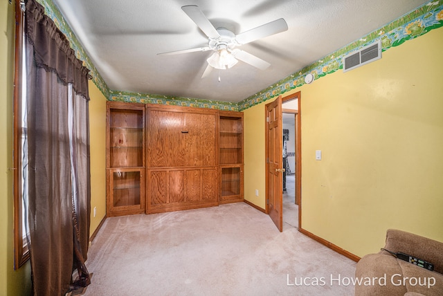 unfurnished bedroom featuring ceiling fan, a textured ceiling, and light colored carpet