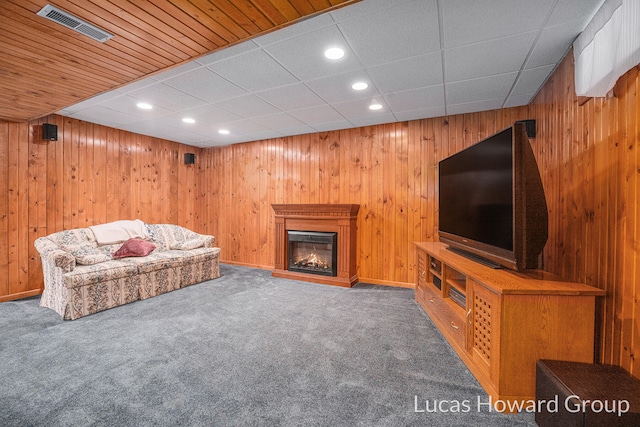 carpeted living room featuring wooden walls