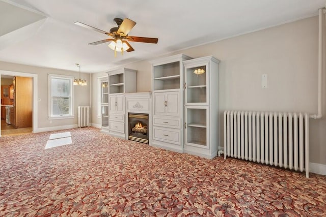 unfurnished living room with carpet flooring, ceiling fan with notable chandelier, and radiator