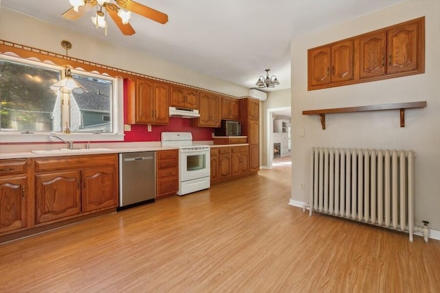 kitchen featuring appliances with stainless steel finishes, hanging light fixtures, radiator heating unit, and light hardwood / wood-style floors