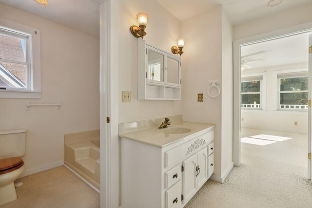 bathroom with vanity, a bathtub, toilet, and plenty of natural light