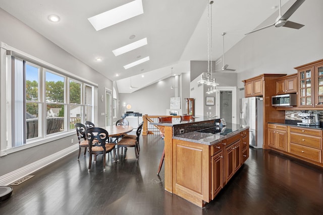 kitchen featuring a breakfast bar area, dark wood-type flooring, stainless steel appliances, a center island, and ceiling fan