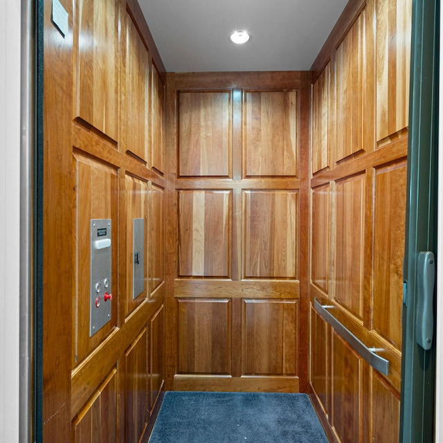 interior details featuring wood walls, carpet flooring, and elevator