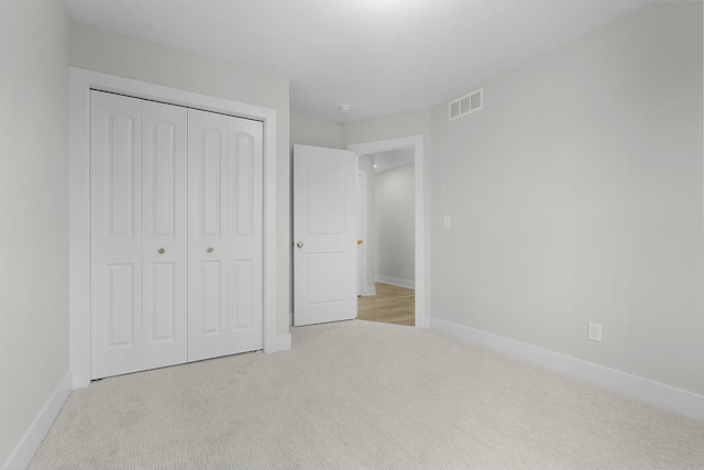 unfurnished bedroom with light carpet and a closet