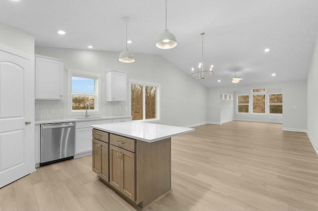 kitchen with dishwasher, a kitchen island, tasteful backsplash, lofted ceiling, and white cabinets