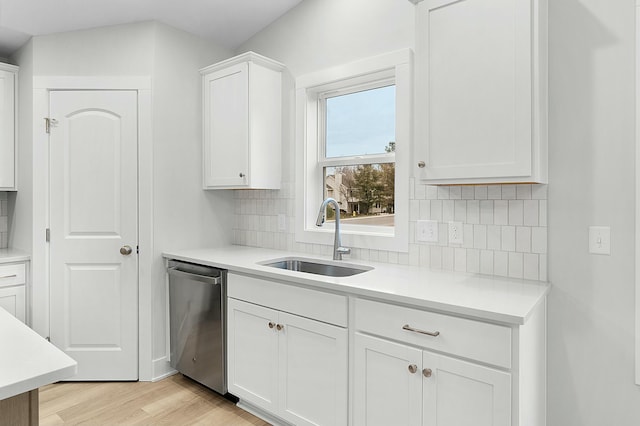 kitchen featuring decorative backsplash, white cabinetry, stainless steel dishwasher, and sink