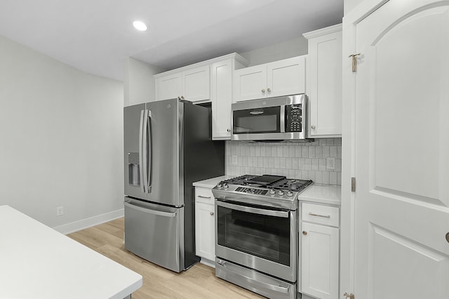 kitchen with backsplash, light wood-type flooring, white cabinetry, and stainless steel appliances