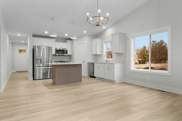 kitchen with a kitchen island, white cabinets, pendant lighting, and appliances with stainless steel finishes