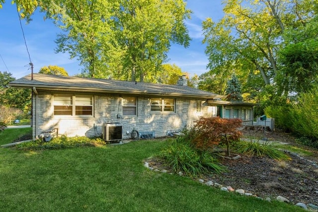 rear view of property with a yard and central air condition unit