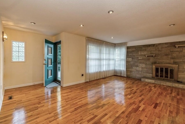 unfurnished living room featuring a textured ceiling, a fireplace, and light wood-type flooring