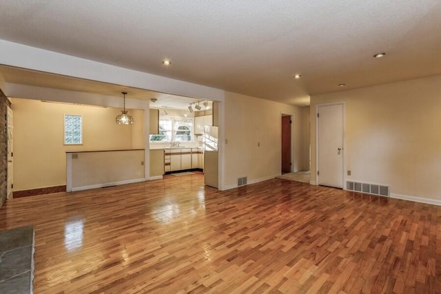 unfurnished living room featuring light wood-type flooring, baseboards, and visible vents