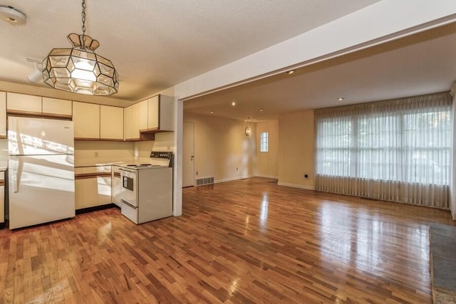 kitchen featuring hardwood / wood-style floors, pendant lighting, and white appliances