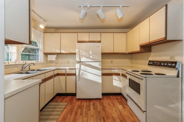 kitchen featuring a sink, light wood-style flooring, white appliances, light countertops, and rail lighting
