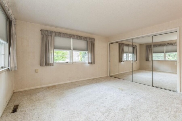 unfurnished bedroom with carpet flooring, a closet, and multiple windows